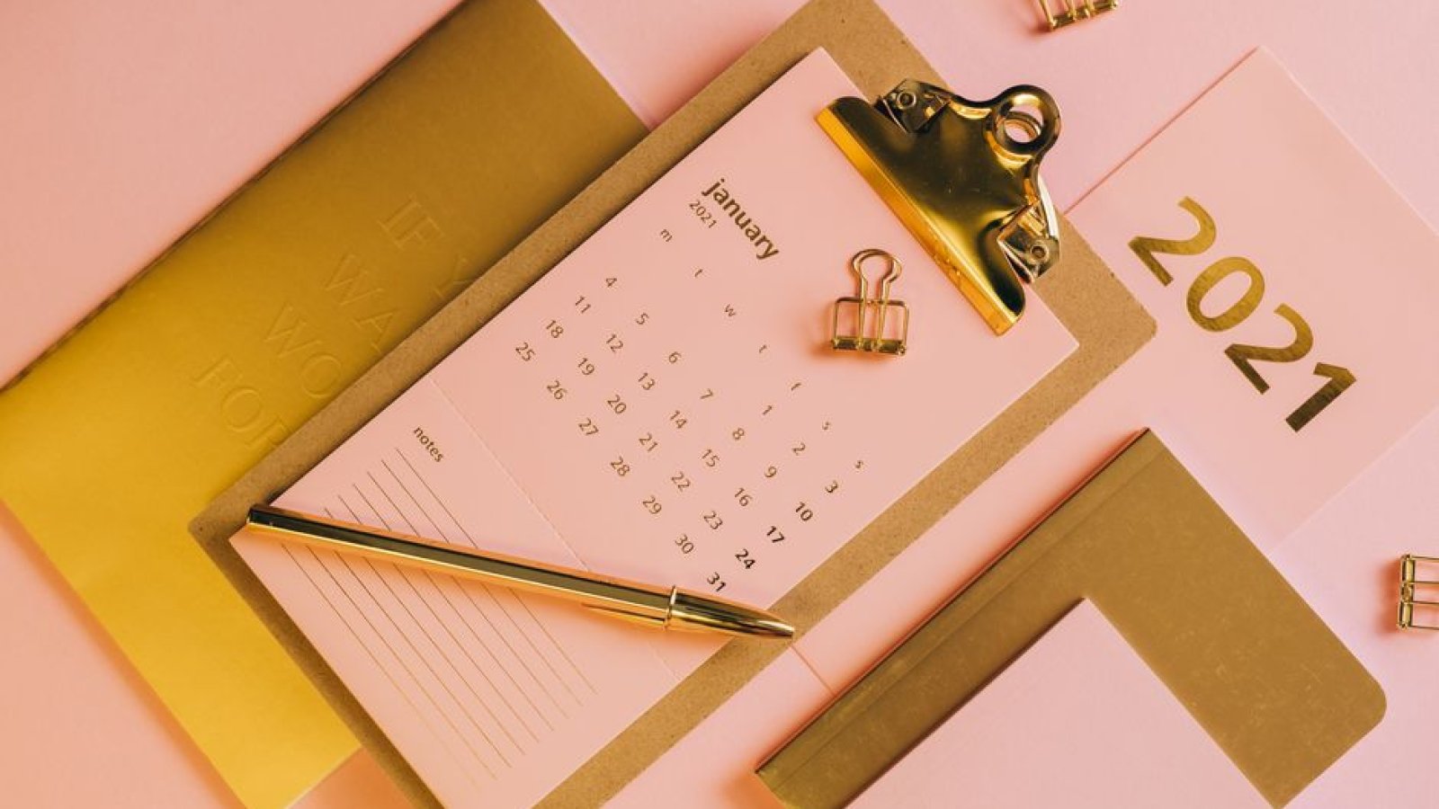 Un calendrier de bureau, un carnet et un stylo posés sur un plan de travail