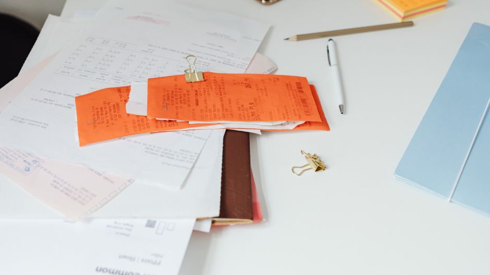 Pile de factures et de documents comptables posée sur un bureau de travail