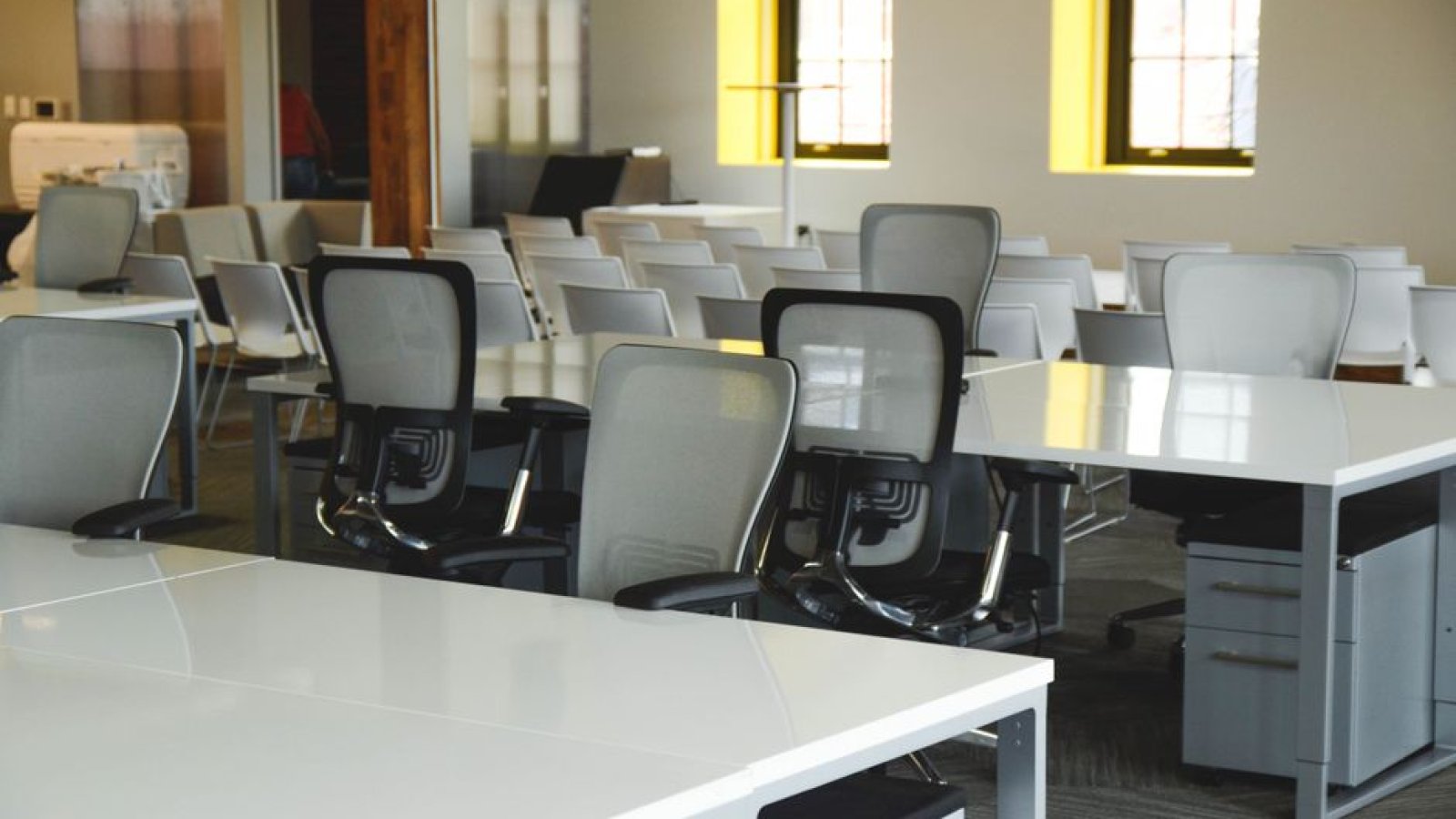 Un bureau vide avec une chaise inoccupée devant une fenêtre, dans un espace de travail sobre.