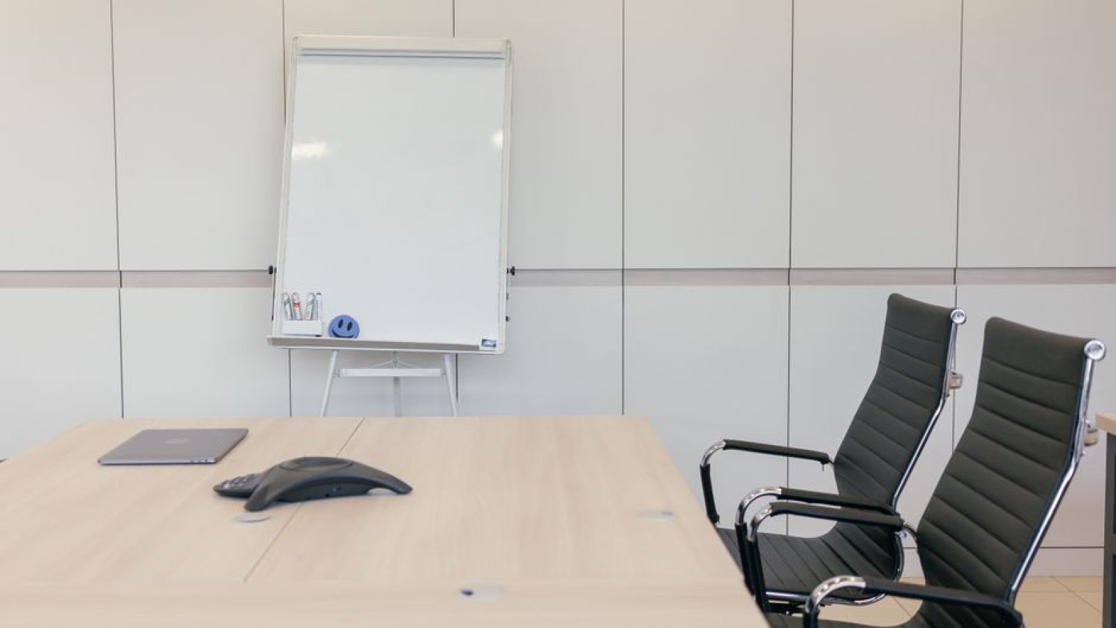 Table de réunion vide entourée de chaises dans une salle de bureau lumineuse