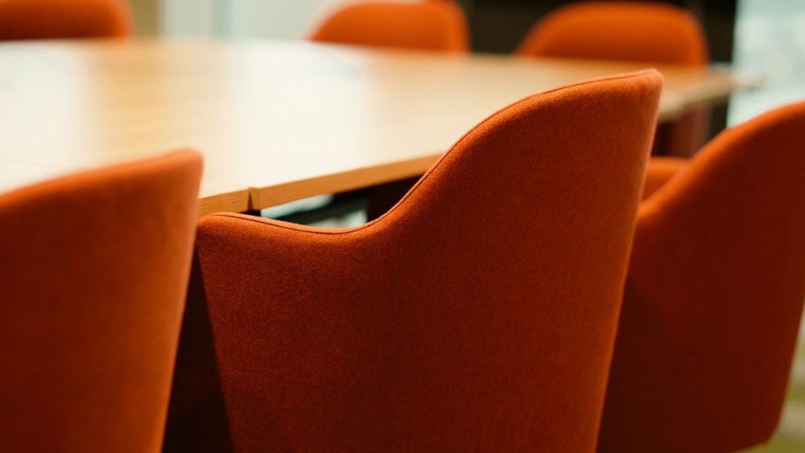 Une salle de réunion vide, avec plusieurs chaises disposées autour d'une table de travail